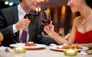 hands of couple toasting their wine glasses over a restaurant table during a romantic dinner.